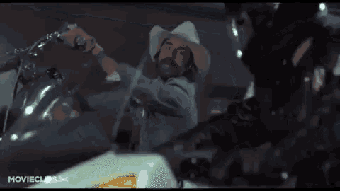 a man in a cowboy hat is talking to another man in a helmet