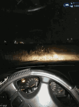 a car is driving down a road at night and the dashboard has a tachometer and a speedometer on it
