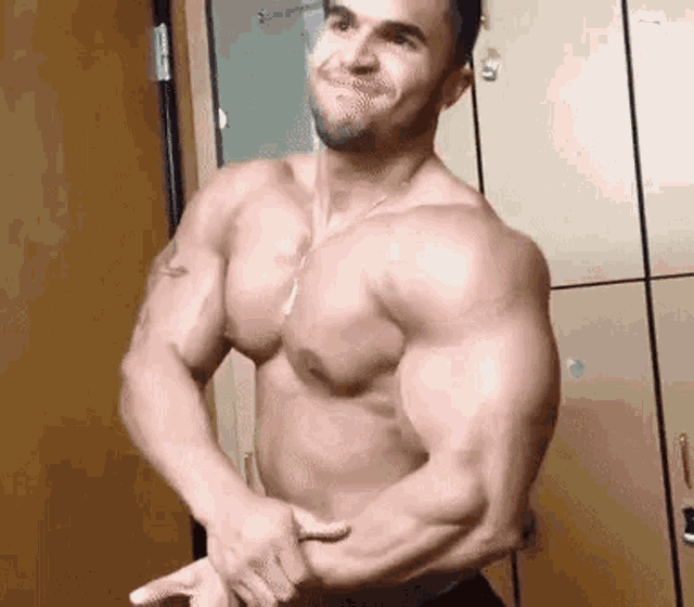 a shirtless man is standing in front of a row of lockers .