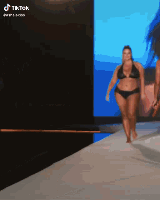 a woman in a bikini walks down a runway with a tiktok watermark on the bottom