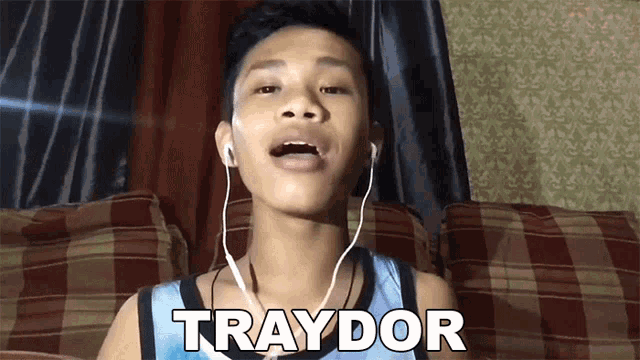 a young boy wearing headphones says traydor in front of a couch