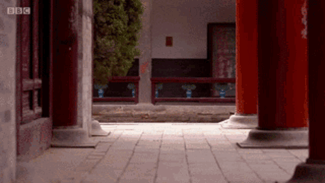 a bbc logo can be seen on a building with red pillars