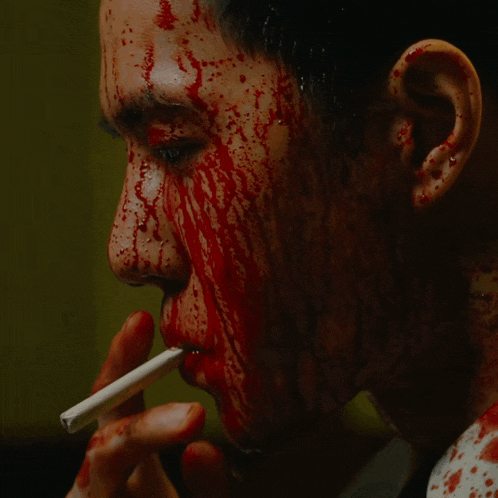 a man with blood coming out of his face is smoking a cigarette