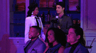 a group of people sitting in a room with purple lights on