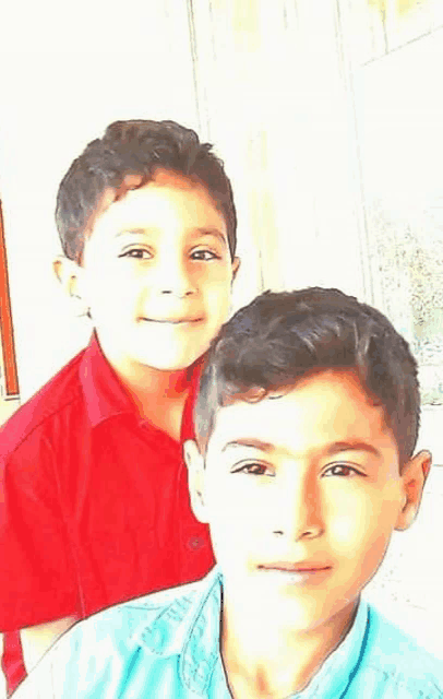 two young boys are posing for a picture together and smiling .