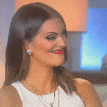 a woman wearing earrings and a necklace with a h on it