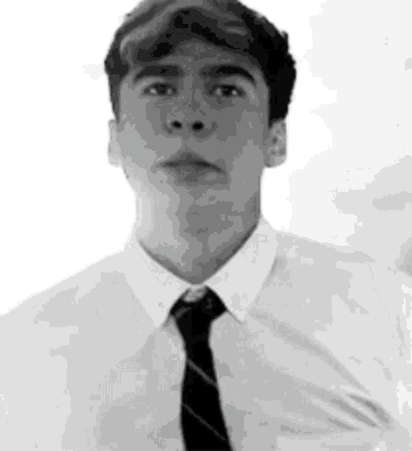a black and white photo of a man wearing a white shirt and black tie .
