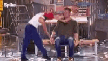two men are standing next to each other on a stage and one of them is holding the other 's hand .