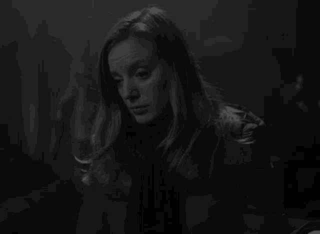a black and white photo of a woman covering her mouth with her hand .