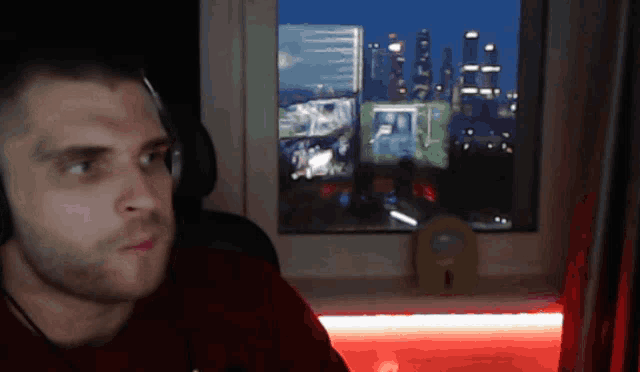 a man wearing headphones looks out of a window at night