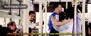 a man in a blue shirt is holding a woman in his arms while another man looks on .
