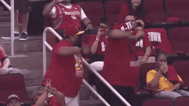 a group of people are sitting in a stadium wearing red shirts that say rockets on them .