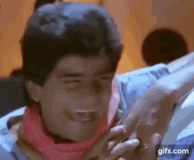 a man wearing a scarf around his neck is making a funny face while holding another man 's hand .