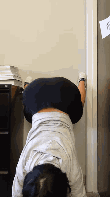 a woman is doing a handstand against a wall in front of a filing cabinet