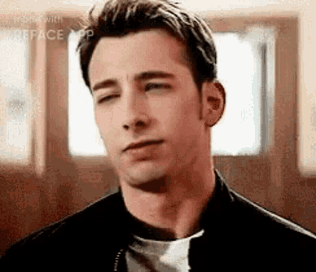 a man with his eyes closed is wearing a black jacket and a white t-shirt .