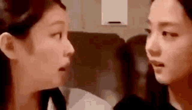 two women are looking at each other in a room and making funny faces .