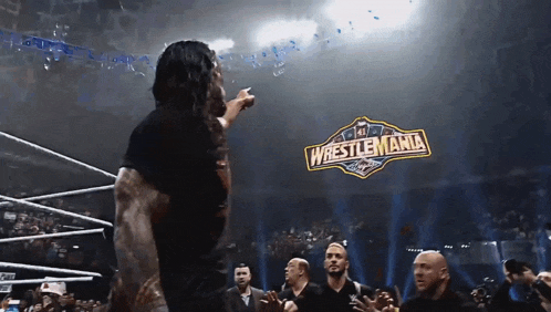 a man stands in front of a sign that says wrestlemania on it