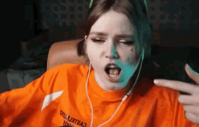 a girl wearing headphones and an orange shirt is sitting in a chair .