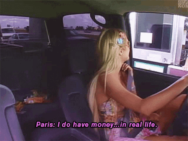 a woman is driving a car and says " paris i do have money ... in real life "