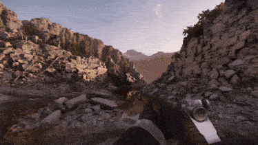 a person holding a gun in front of a rocky mountain