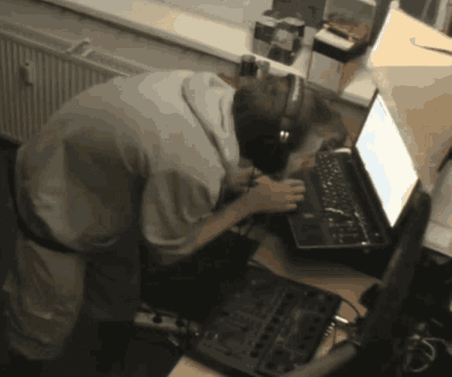 a man wearing headphones is using a laptop computer