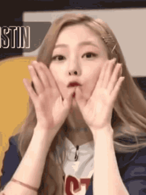 a woman making a face with her hands in front of a sign that says stin