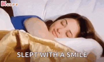 a woman is sleeping with a smile on her face .