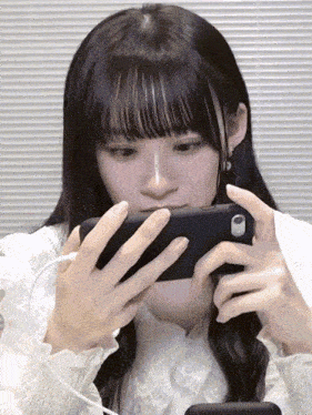 a girl with long black hair is playing a game on her cell phone