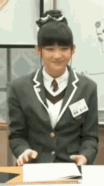 a girl in a school uniform and tie is sitting at a table .