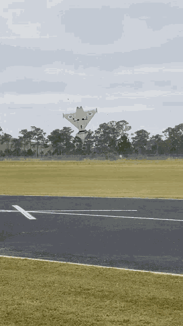 a plane is taking off from a runway with a white x on the ground