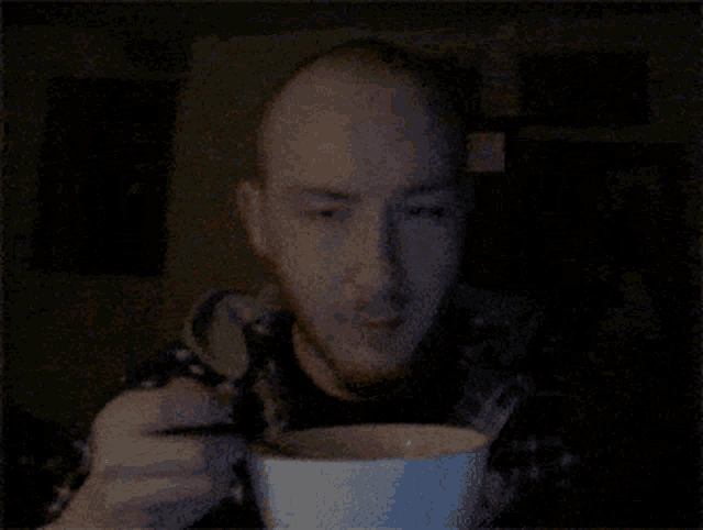 a man with a beard is eating a bowl of soup with a spoon