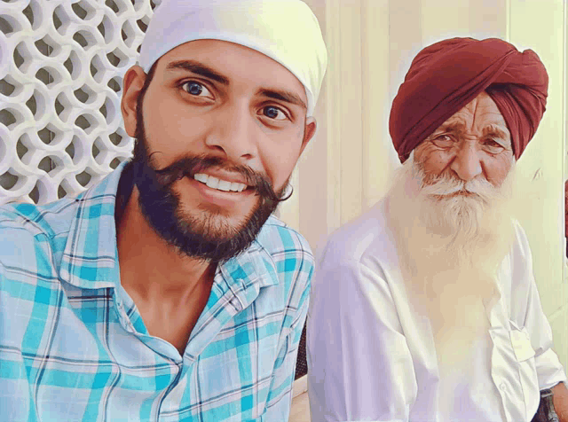a man with a beard and a turban smiles next to another man