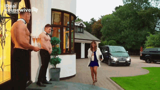 a woman walking in front of a house with a real housewives logo on the bottom