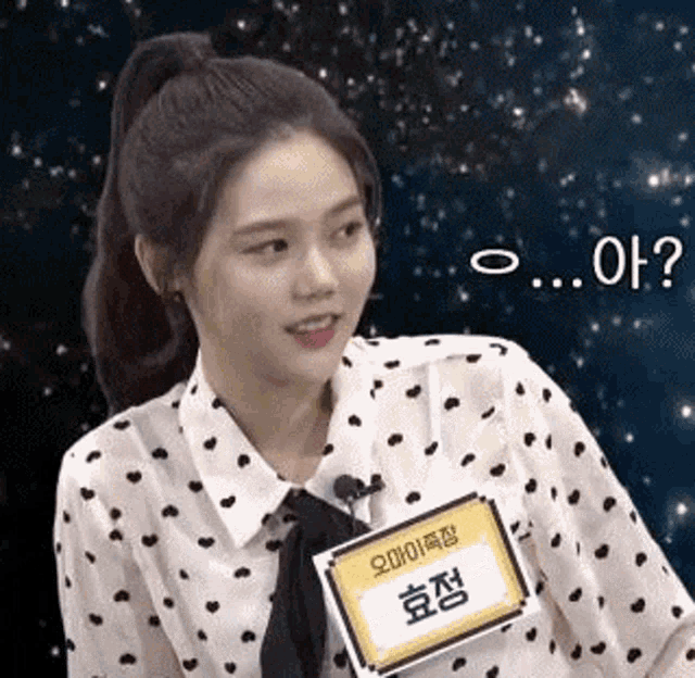 a woman in a polka dot shirt and tie is holding a name tag with a name tag on it .