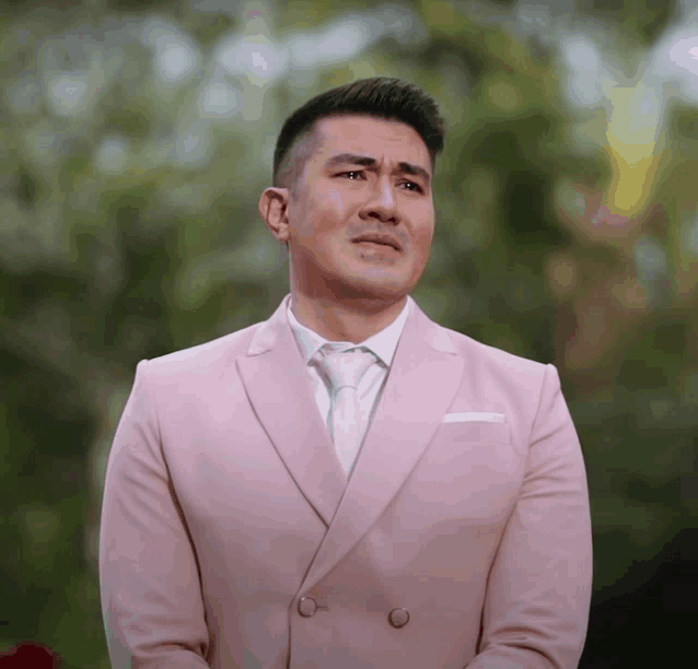 a man in a pink suit and white tie looks down