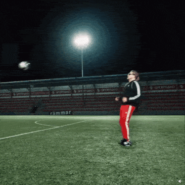 a man kicks a soccer ball on a field with a sign that says rammar