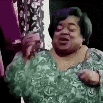 a woman with purple hair is wearing a green floral shirt