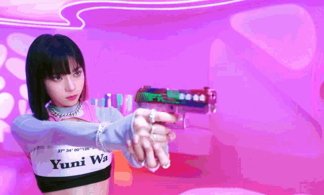 a girl with yuni wa on her shirt is holding a gun