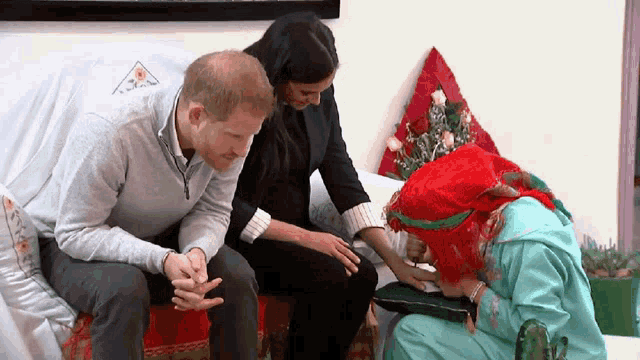 a man and a woman are sitting on a couch talking to a girl in a green dress .