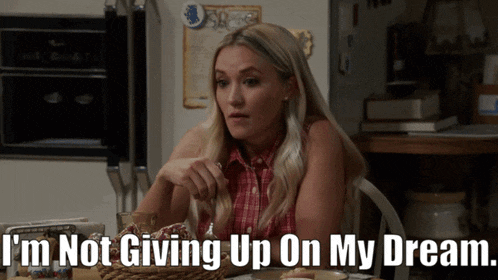 a woman is sitting at a table with the words " i 'm not giving up on my dream "