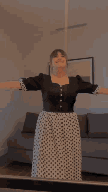 a woman wearing a black and white polka dot dress is standing in front of a mirror