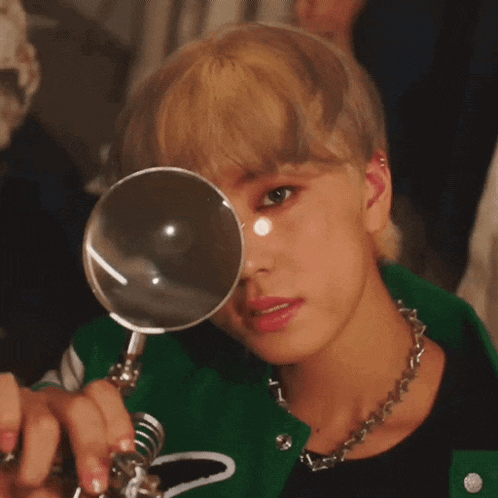 a close up of a person holding a magnifying glass to their eye .