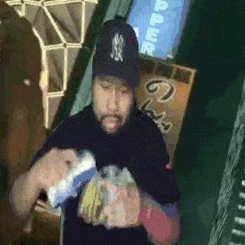 a man wearing a new york yankees hat holds a bag of chips