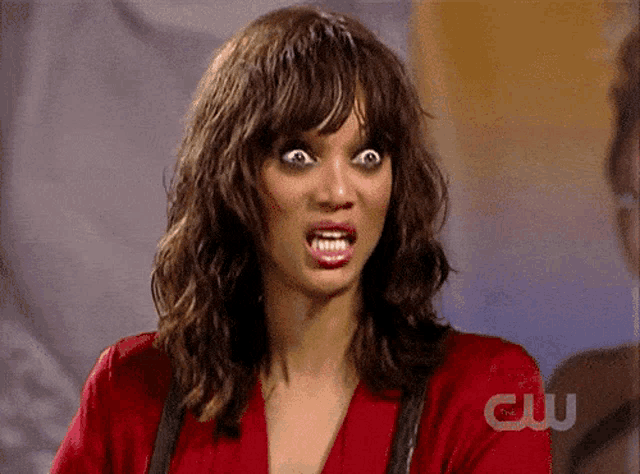 a woman is making a funny face in front of a cw sign