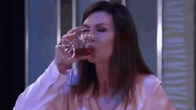 a woman is drinking a glass of wine from a decanter .