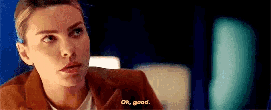 a woman in a brown suit is talking to another woman in a dark room .