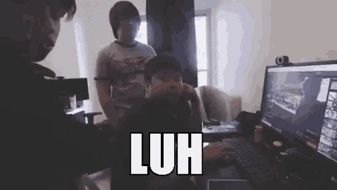 a man is sitting in front of a computer screen with the word luh written on it .