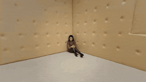a woman is laying on the floor in a room with a square hole in the wall