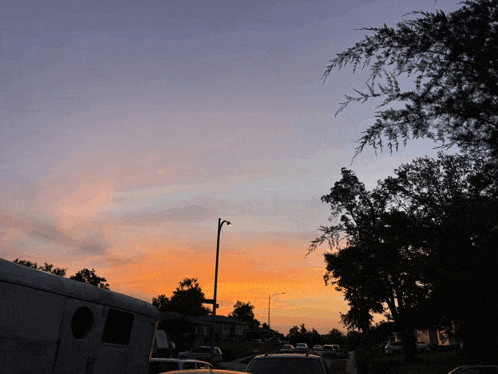 a sunset with a few cars parked in front of a building