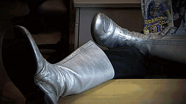 a person wearing a pair of silver boots is laying on a desk
